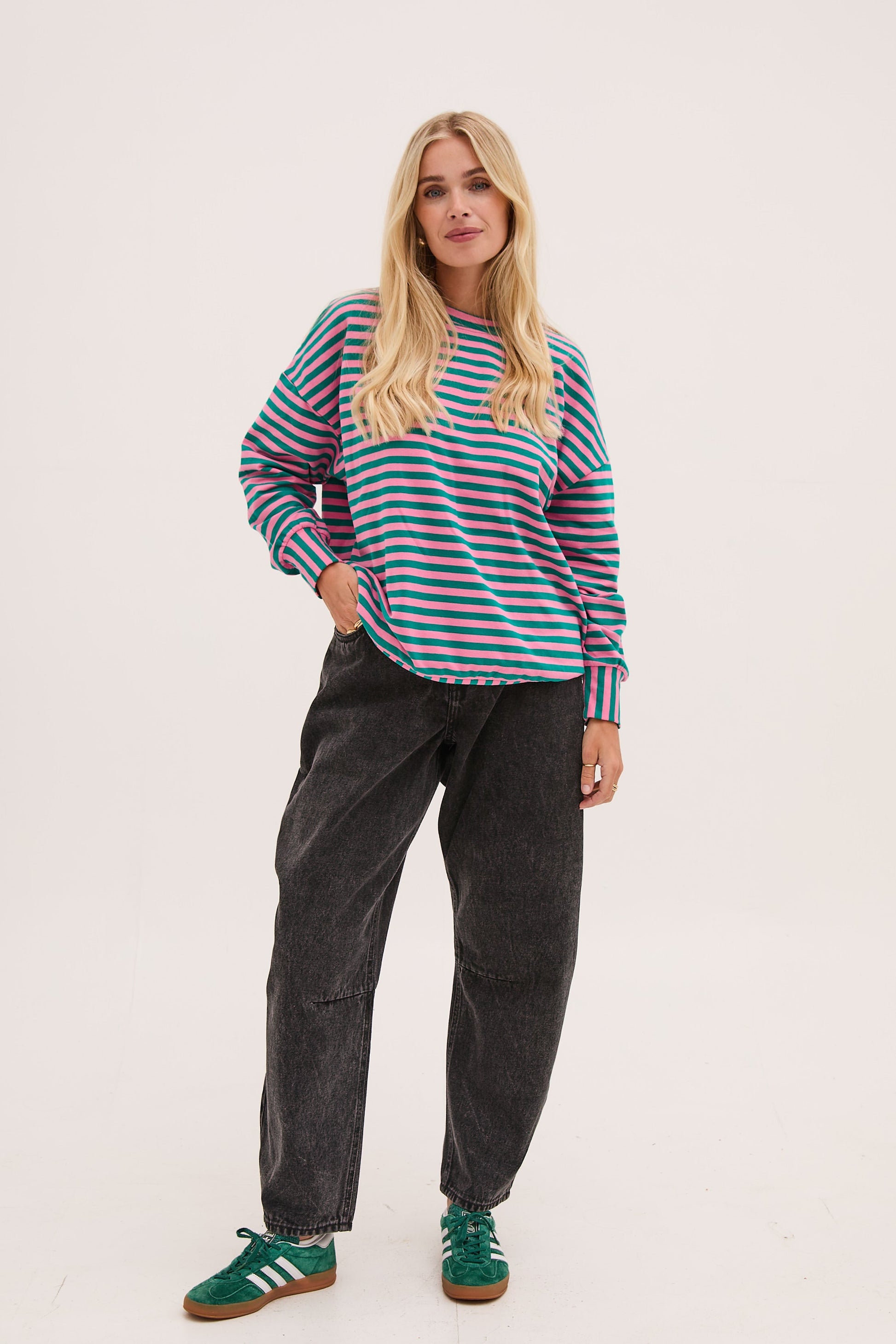Woman wearing a striped sweater and dark pants on a white background