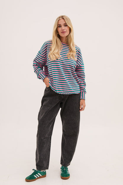 Woman wearing a striped sweater and dark pants on a white background