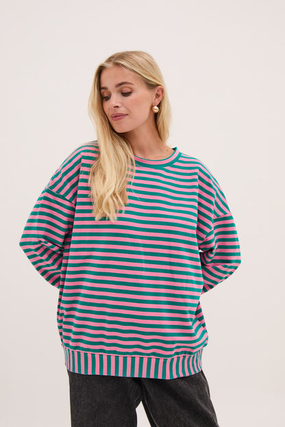 Woman wearing a green and pink striped sweater on a white background